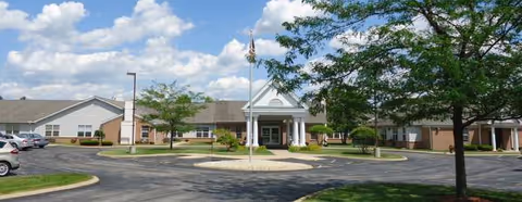 Exterior view of Orchard Grove senior living facility with entrance and parking.