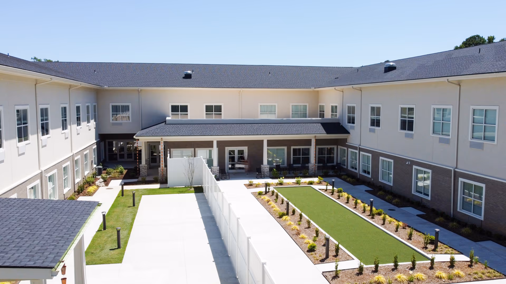 A U-shaped senior living building surrounding a landscaped central courtyard with walkways and seating.