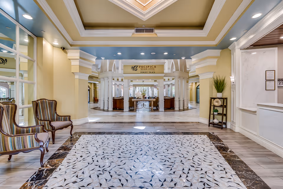 Bright, spacious senior living lobby with patterned marble flooring, decorative columns, seating areas and a central reception under a skylight.
