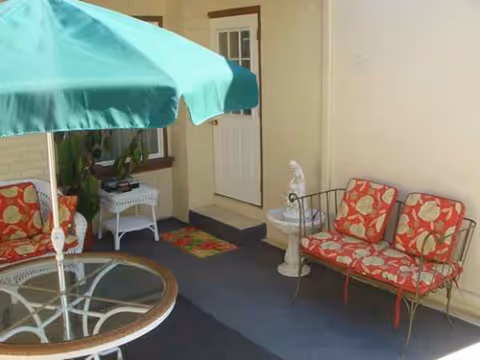 Outdoor patio with red-patterned cushioned seating, umbrella, and doorway into the facility.