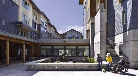 Outdoor courtyard at Creekside Woods with residents seated and a wheelchair nearby.