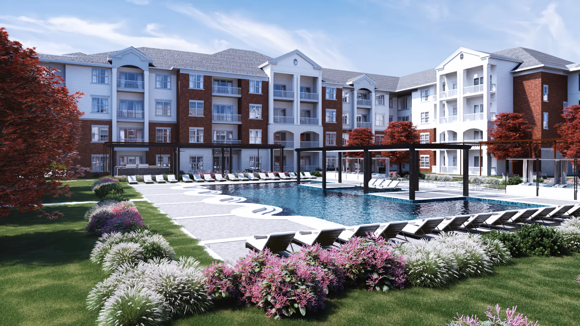 Outdoor view of Jubilation by Silver Companies featuring a large swimming pool surrounded by lounge chairs and pergolas. The pool area is landscaped with green grass, purple and white flowering plants, and red-leaved trees. In the background, there is a multi-story residential building with balconies and a mix of white and brick exterior walls under a partly cloudy sky.