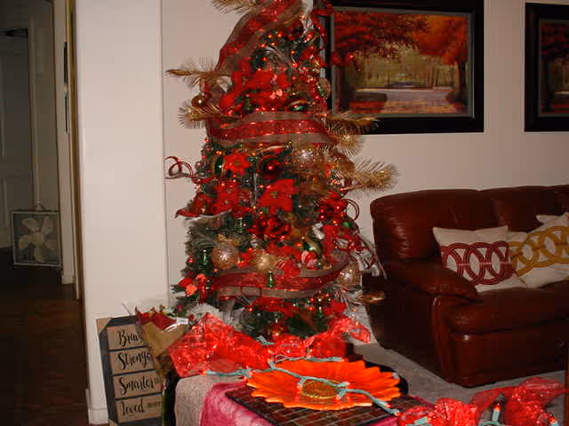 Living room interior with a decorated Christmas tree, wrapped presents, and a leather sofa.