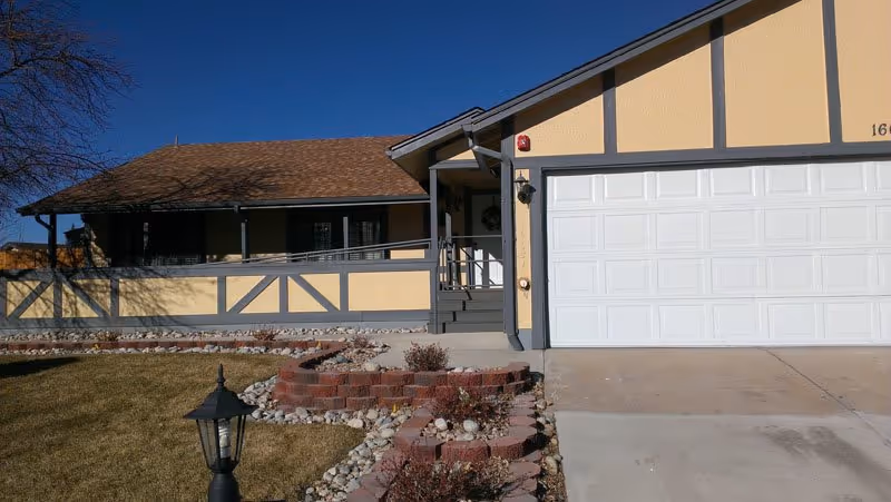 Front exterior of Cardan Manor Assisted Living building with a garage, porch, and landscaped walkway.
