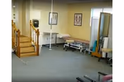 Interior rehab area with staircase, treatment table, seating, and framed wall art.