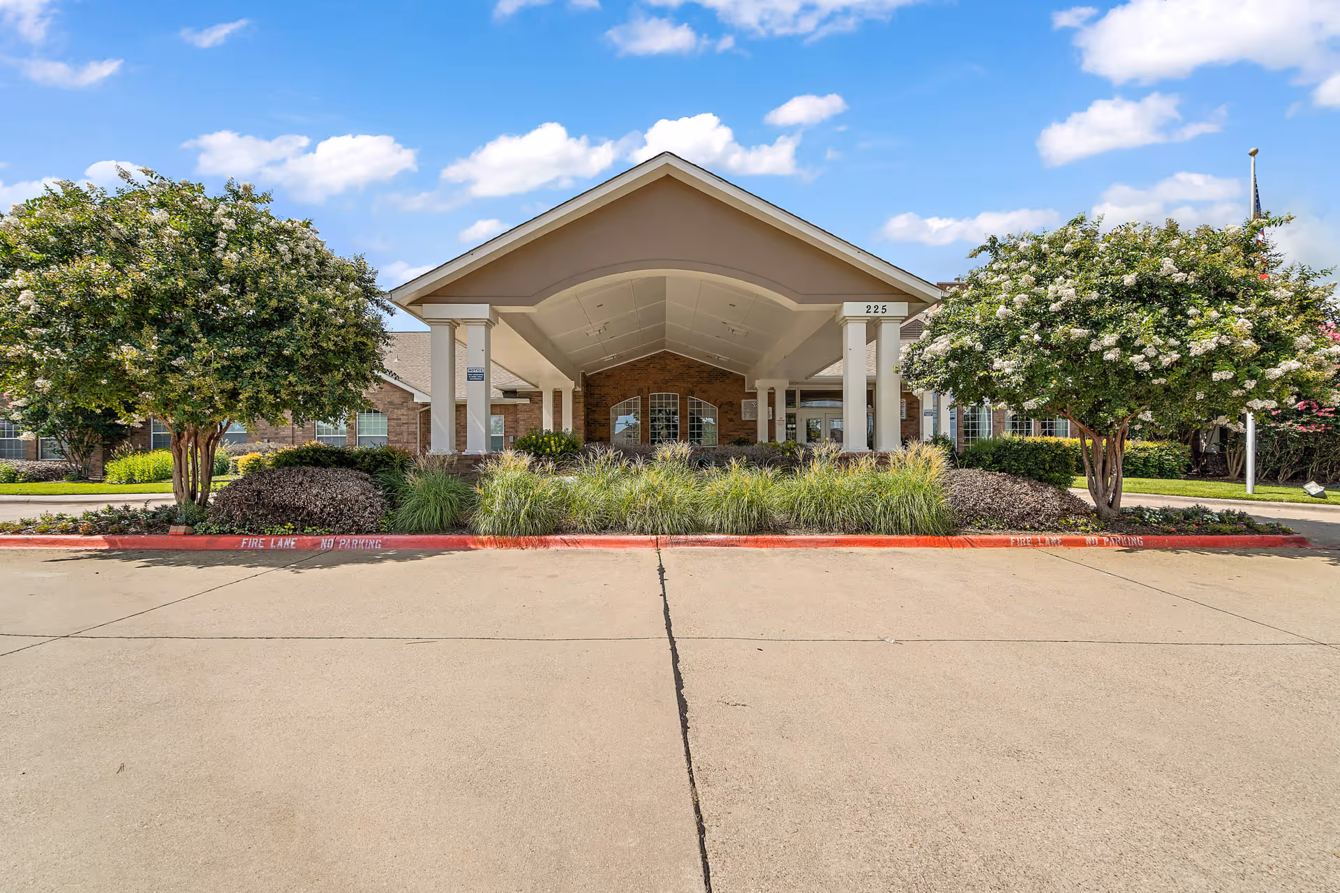 Front view of Morada Cedar Hill II entrance with curved canopy and landscaped shrubs