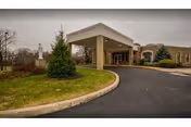 Entrance of St. John Neumann Center for Rehabilitation and Healthcare with curved driveway and landscaped grounds.