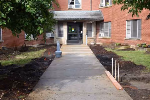 Milton Home entrance with a concrete walkway leading to a glass door.