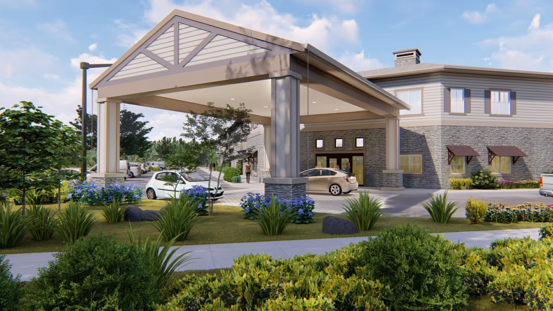 Exterior view of The Lodge at Piner Road showing the entrance with a covered drop-off area supported by large pillars. There are cars parked near the entrance, landscaped greenery with bushes and flowers, and a sidewalk in the foreground. The building has stone and siding exterior with multiple windows and a clear blue sky above.
