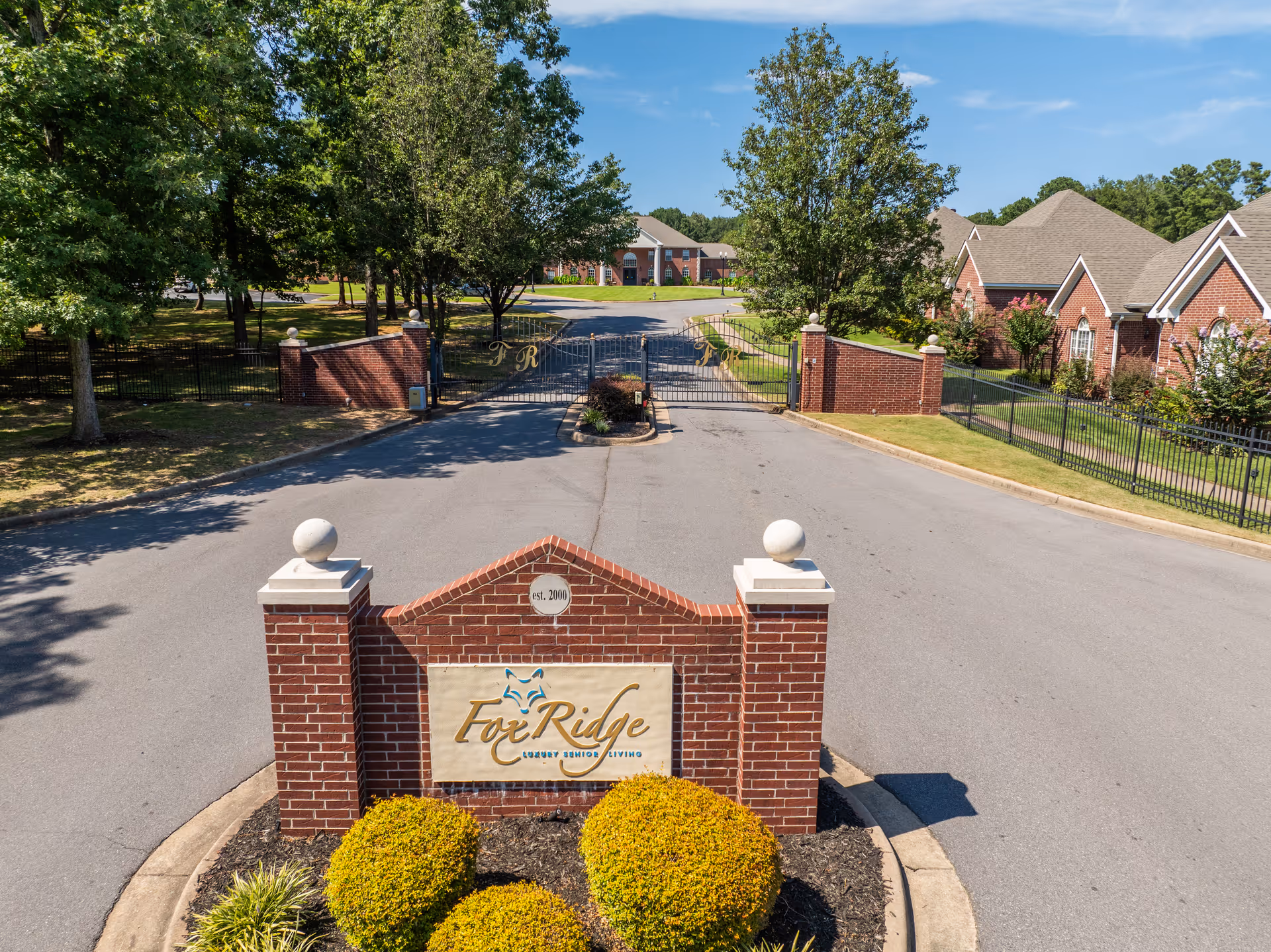 Entrance to Fox Ridge Bryant senior living facility featuring a sign and landscaped surroundings.