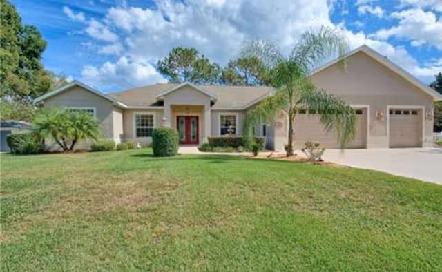 Front exterior of a single-story beige house with a manicured lawn, palm trees, and a three-car garage under a partly cloudy sky.
