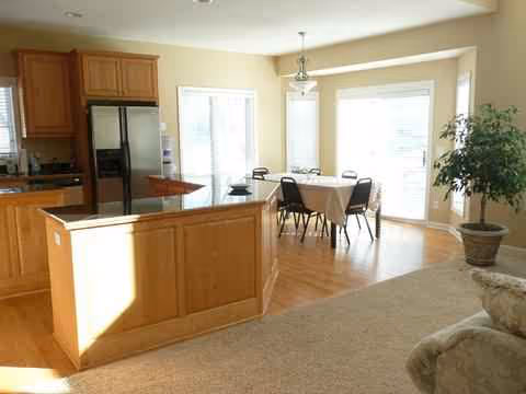 Open-concept kitchen and dining area with wooden island, table, chairs, and potted plant.