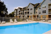 Outdoor pool area with lounge chairs in front of a multi-story senior living building.