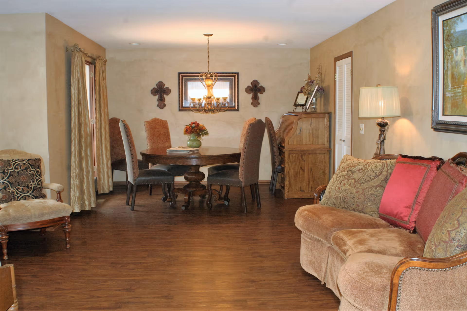 Cozy living and dining area with a sofa, round dining table, chandelier, and wood flooring.