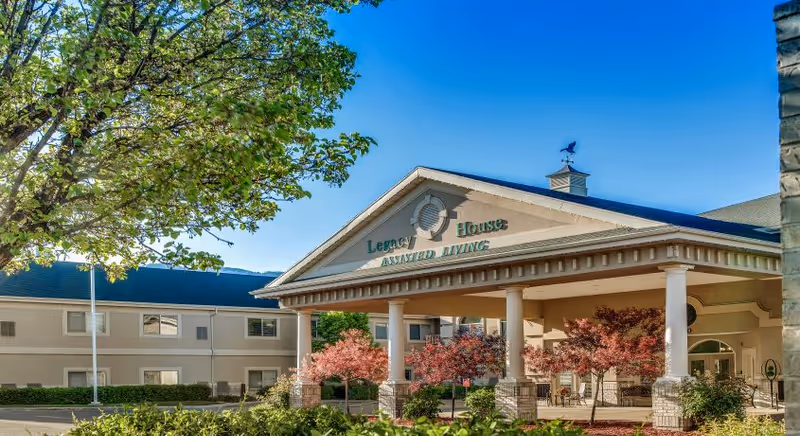 Front view of Legacy House Assisted Living exterior with entrance columns and landscaped grounds.