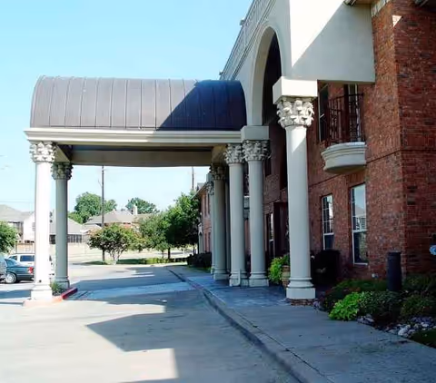 Exterior view of a senior living facility entrance with arches and columns.