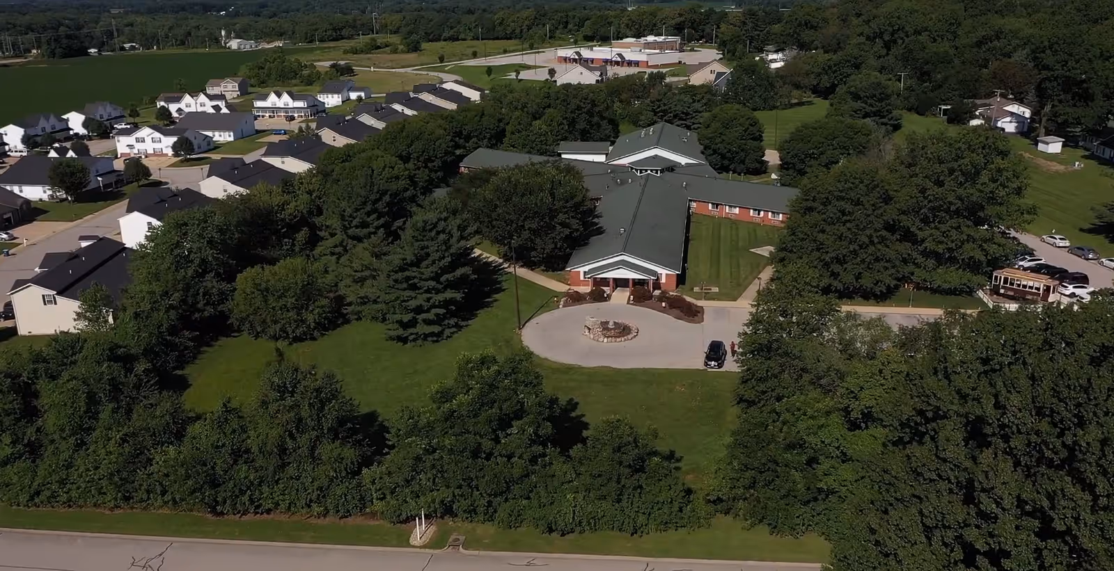 Aerial view of Cedar Ridge Health & Rehab Center showing a green‑roofed single‑story building with a circular driveway, lawns and trees, beside a residential neighborhood.