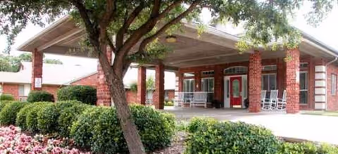 Front entrance of Brookdale Denton South with brick columns, a covered walkway, and greenery.