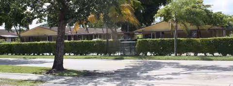 Exterior view of Avalon Park Retirement Residence with trees, hedges, and a front walkway.