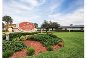 Front lawn and entrance sign for West Melbourne Health and Rehabilitation Center in front of a low, single-story building with palm trees.