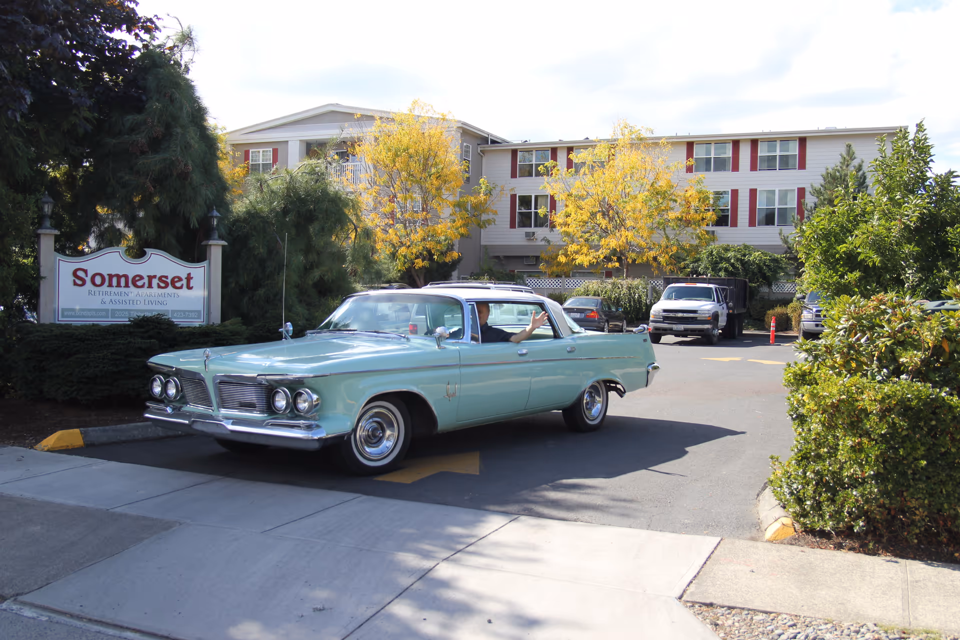 Front exterior of Somerset Retirement Home with a vintage turquoise car parked in the driveway and the facility sign visible.