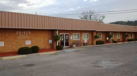 Single-story brick facility exterior with entrance doors and row of windows.
