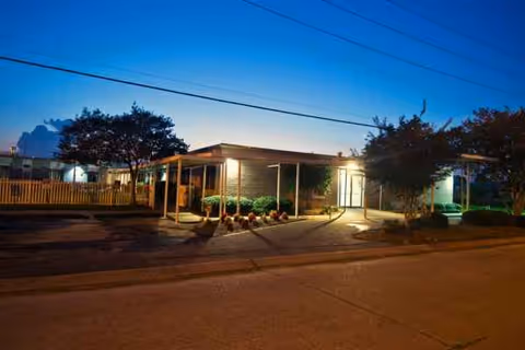 Exterior view of a single-story senior care center at dusk with entrance canopy