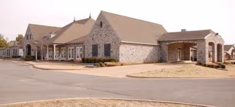 Stone-faced senior living facility with multiple entrances and a curved driveway at the front.