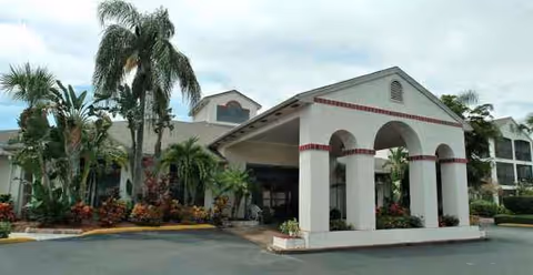 Front view of Regency Residence Sky Active Living building with arches, palm trees, and landscaping.