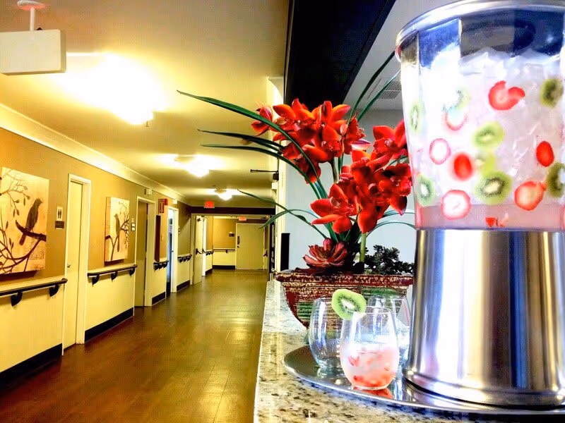 Interior hallway with wall art, handrails, and a floral arrangement on a counter.