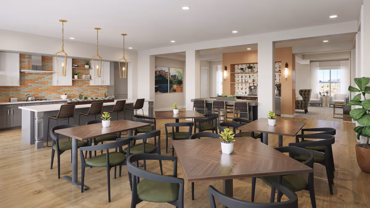 A modern dining area in a senior living facility featuring several wooden tables with green cushioned chairs. The space includes a kitchen area with a long island, bar stools, pendant lighting, and a colorful tiled backsplash. In the background, there is a lounge area with armchairs and large windows letting in natural light.