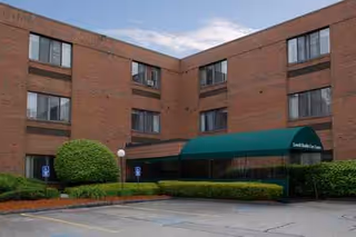 Brick exterior of CareOne at Lowell with green awning entrance.