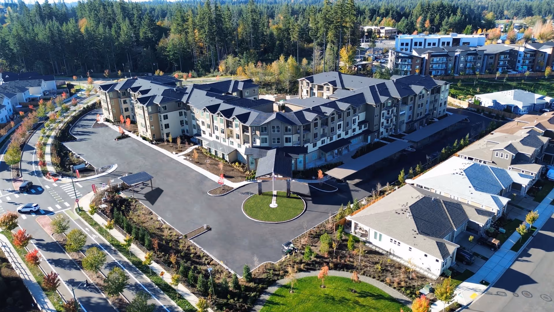 Aerial view of Bonaventure of Maple Valley senior living facility showing a large multi-story building with a circular driveway and landscaped grounds surrounded by trees and nearby residential houses.
