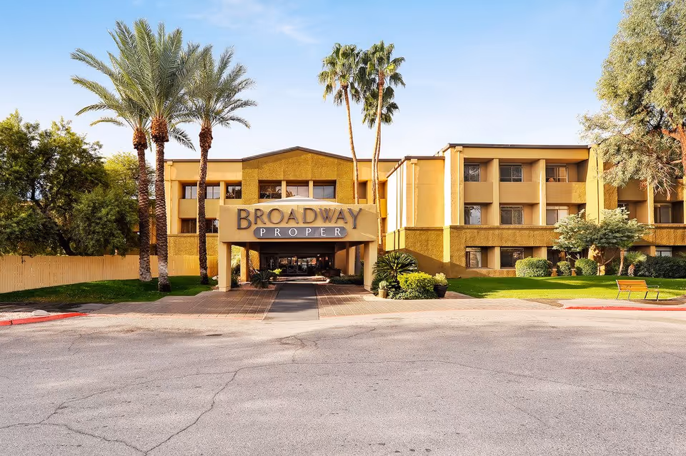 Exterior view of Broadway Proper Assisted & Senior Living building with palm trees and entrance