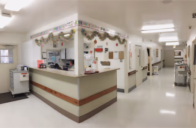 A nurse station reception desk in a brightly lit care facility hallway decorated with garlands.