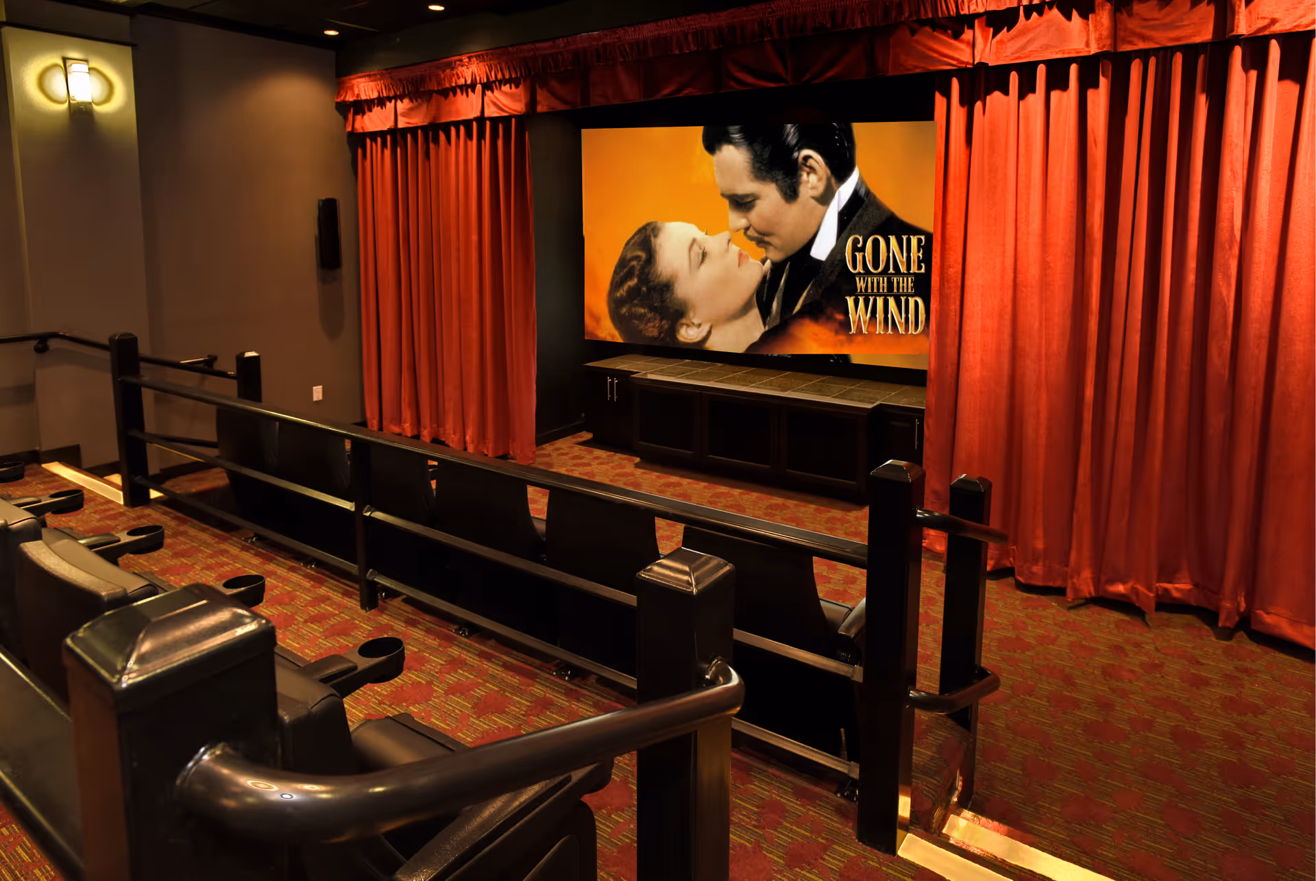Small screening room with red curtains, theatre seating, and a screen showing a 'Gone With the Wind' poster.