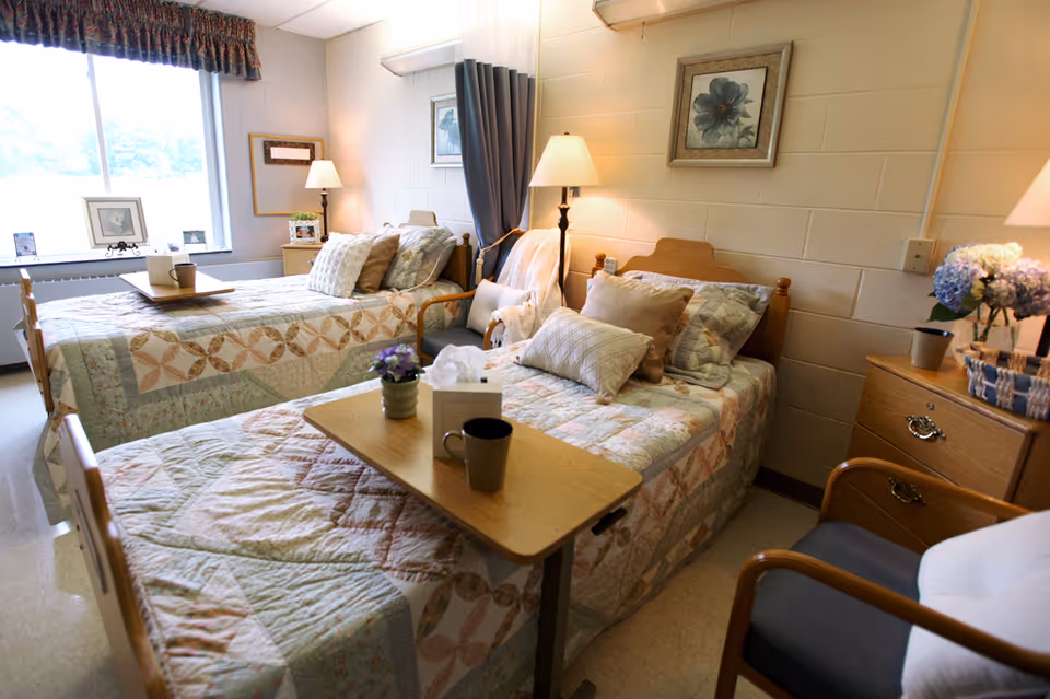A bright, neatly arranged twin bedroom with two single beds, bedside tables, lamps, and a window.