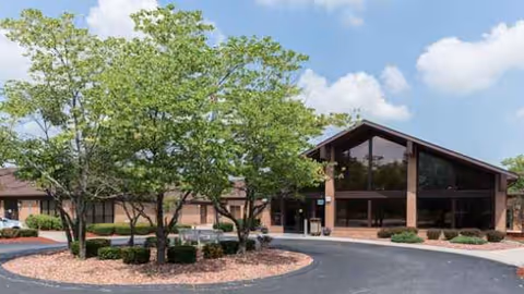 Exterior view of ALIYA of Homewood with trees, shrubs, and the entrance.
