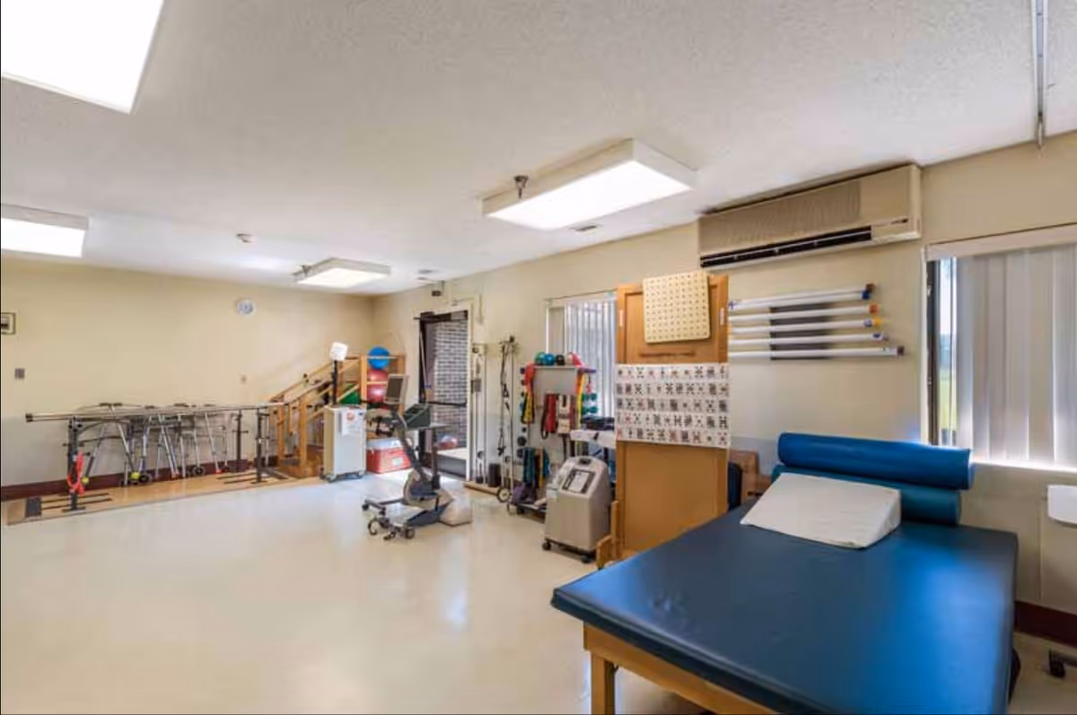 Rehabilitation therapy room with treatment table and exercise equipment.