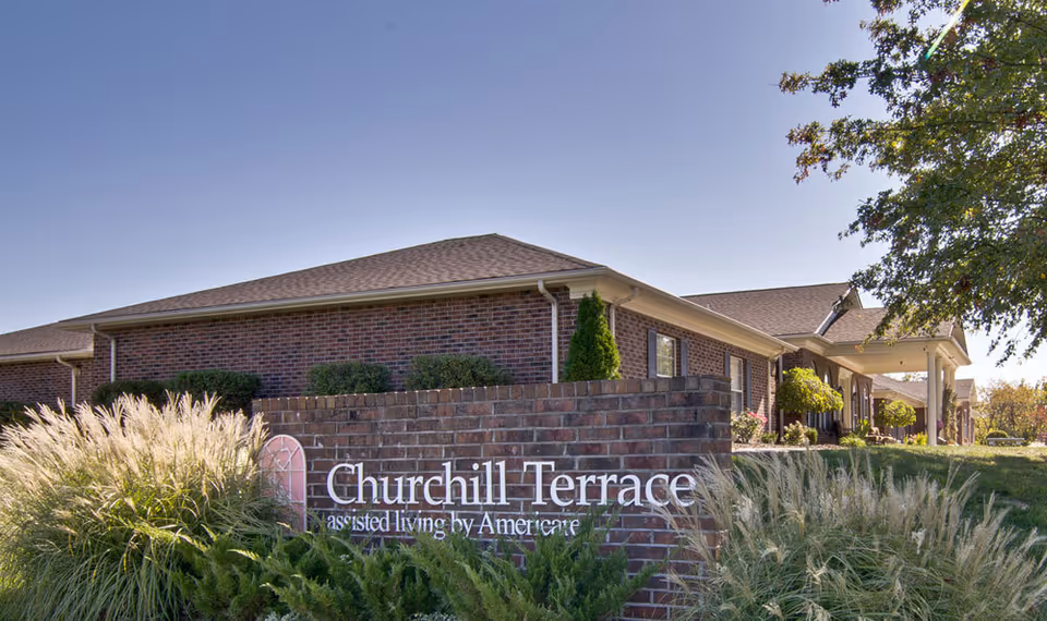 Brick senior living building front with a Churchill Terrace sign and landscaped entry.