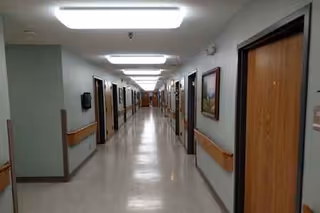 Long, well-lit hallway in a senior living facility with doors along both sides