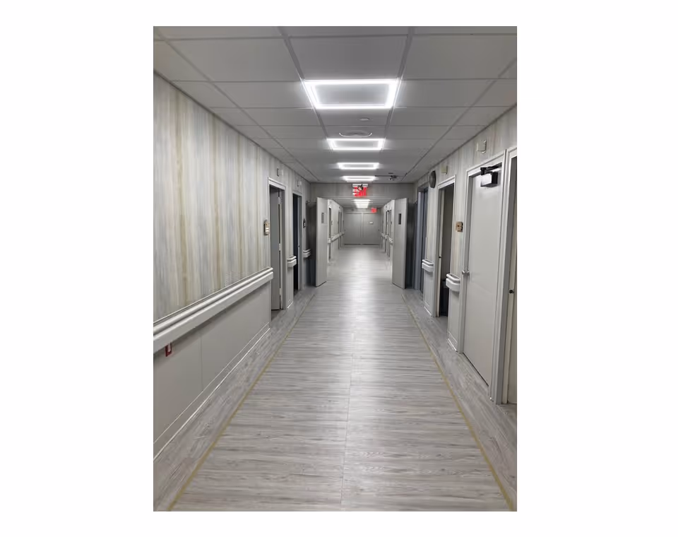 A long, sterile hallway with closed doors along both sides inside a senior living facility.