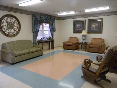Senior living facility lounge with sofa, chairs, window, drapes, and lamps.