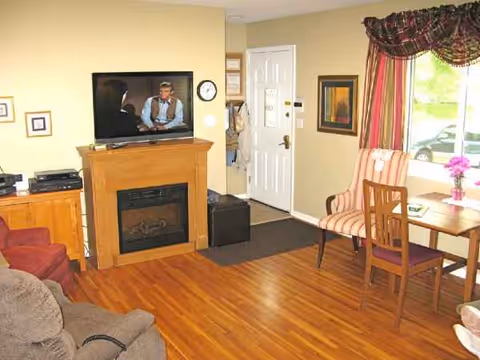 Cozy living room with fireplace, TV, couch, dining table, and large window.