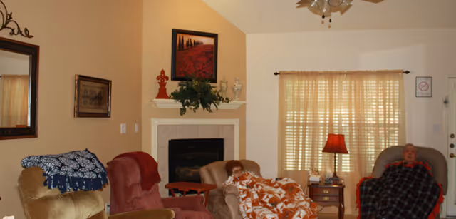 Cozy living room with a fireplace, warm seating, and two residents relaxing.