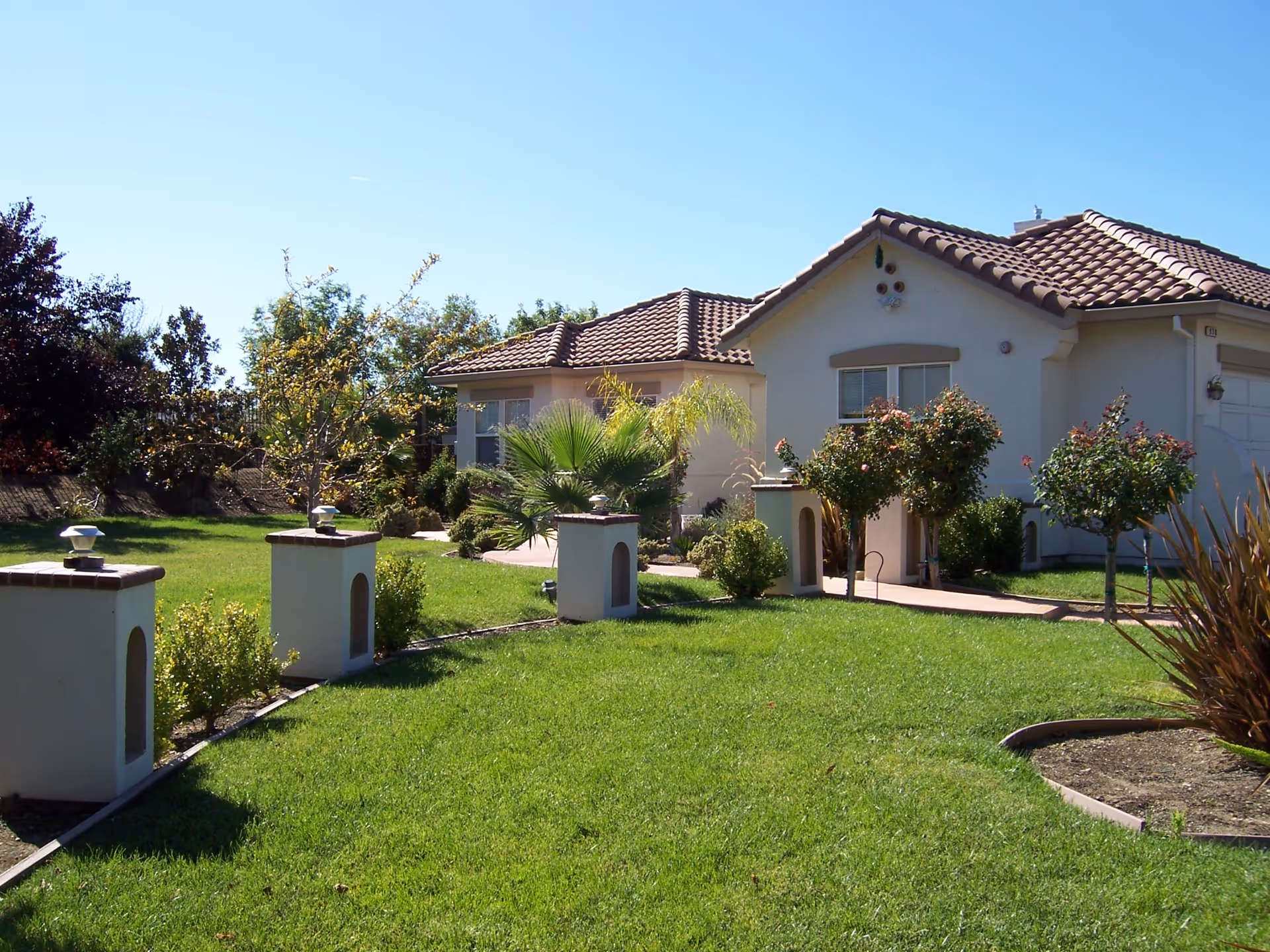 Front view of a single-story stucco house with a tiled roof and a landscaped lawn.
