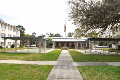 Exterior view of Florida Gulf Coast Apartments with a central walkway and flag.