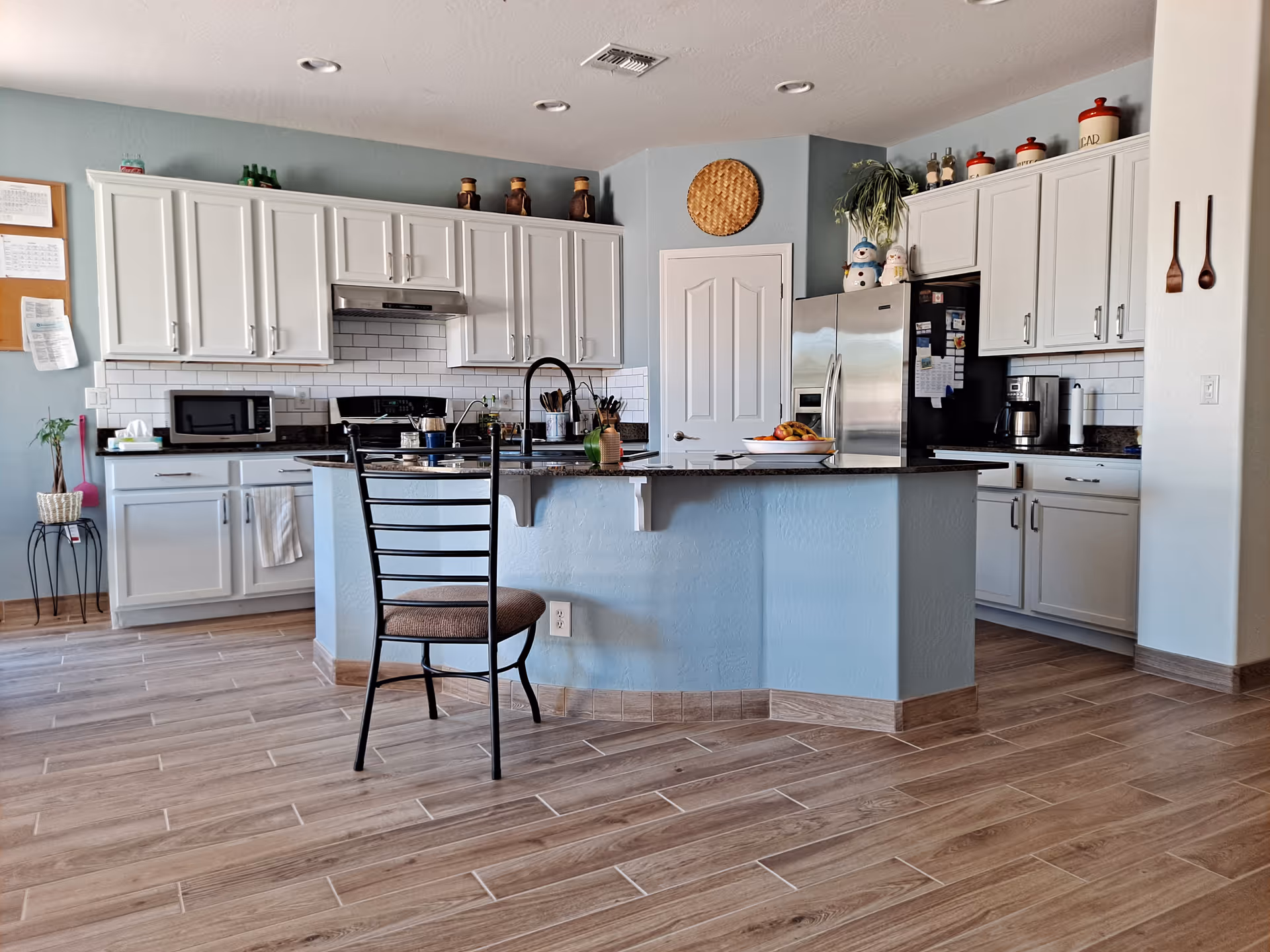 Bright kitchen with white cabinets, a blue island, and stainless appliances.