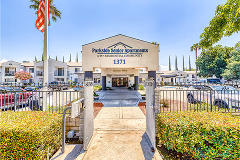 Front entrance to Parkside Senior Apartments with a gated walkway and building sign.
