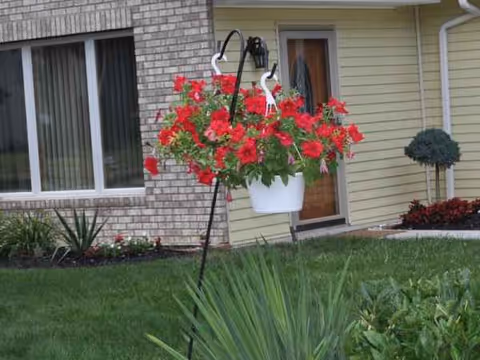 Exterior view of a senior care building with a hanging red flower basket near the entrance.